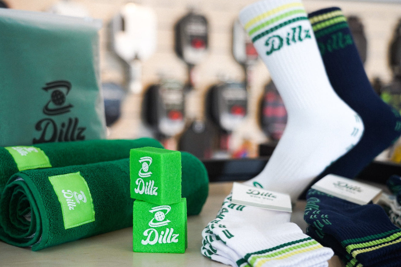 Dillz socks, towels, and wristbands displayed with pickleball paddles