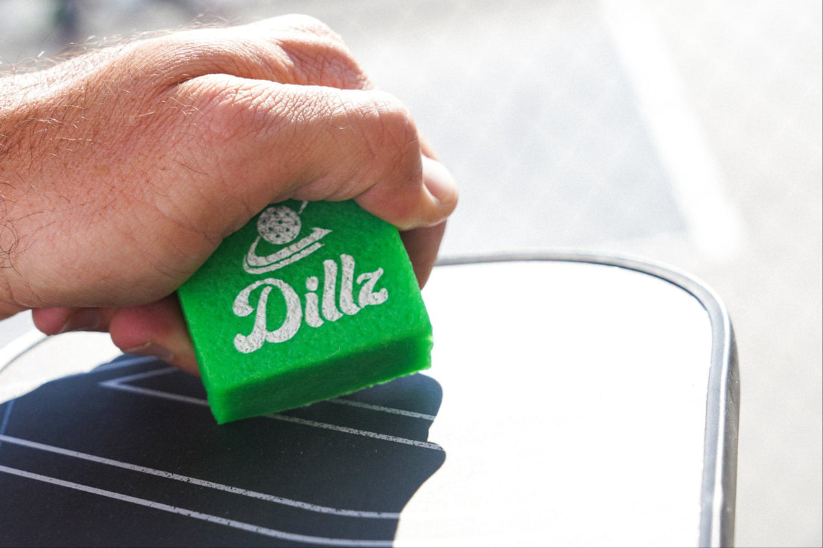 Green Dillz paddle-cleaning eraser being used on a pickleball paddle